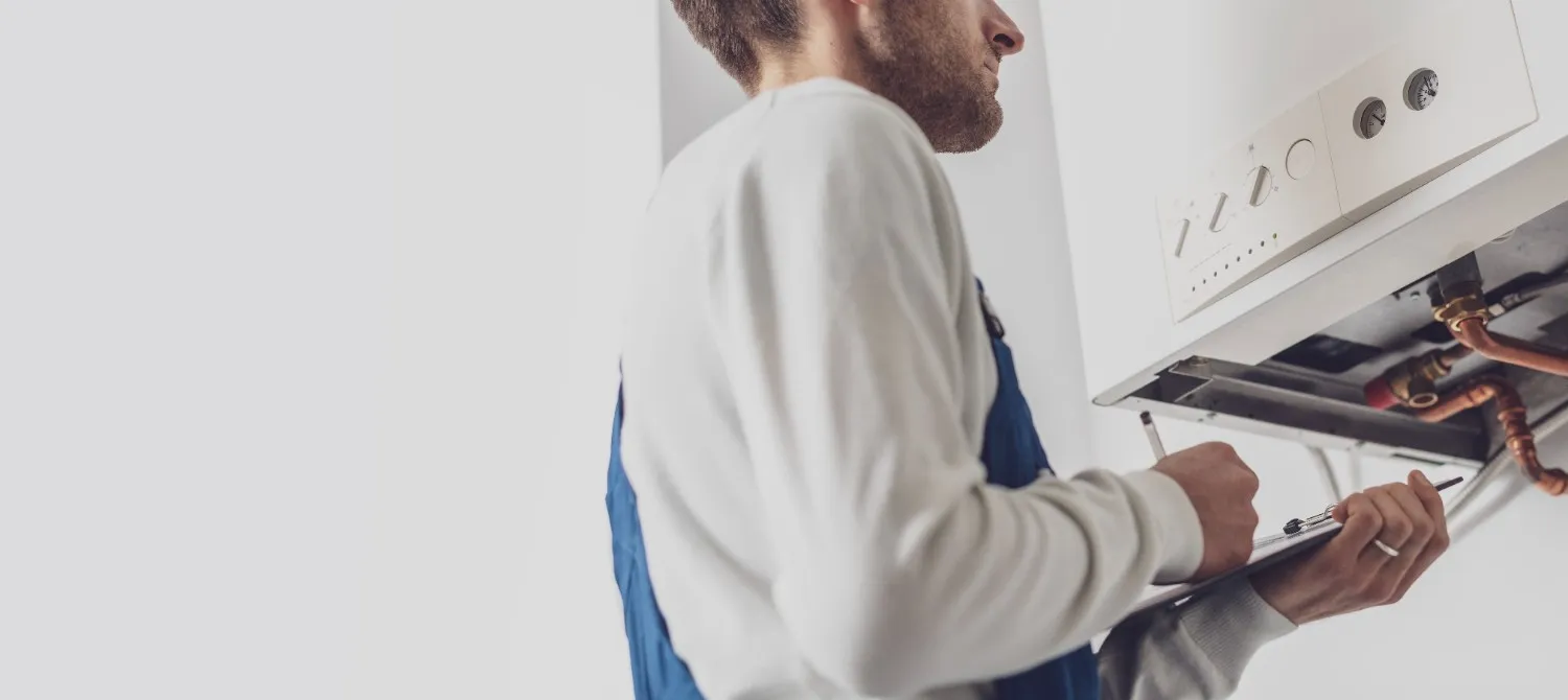 Technician checking the pipes under a wall water heater